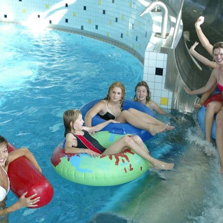 Junge Personen rutschen im Schwimmbad auf einer Wasserrutsche