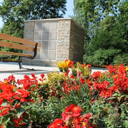 Kolumbarium im Hintergrund, überwiegend rote Blumen im Vordergrund