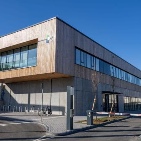 Das Recyclingzentrum Mitte, ein großes Gebäude mit Holzvertäfelung oben  und Fensterreihen.