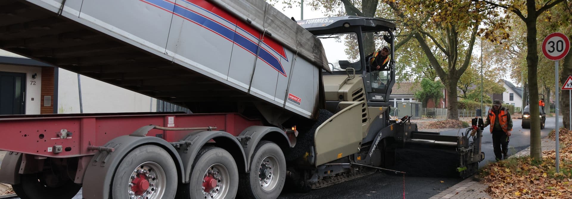 LKW schüttet Material in Straßenbaumaschine