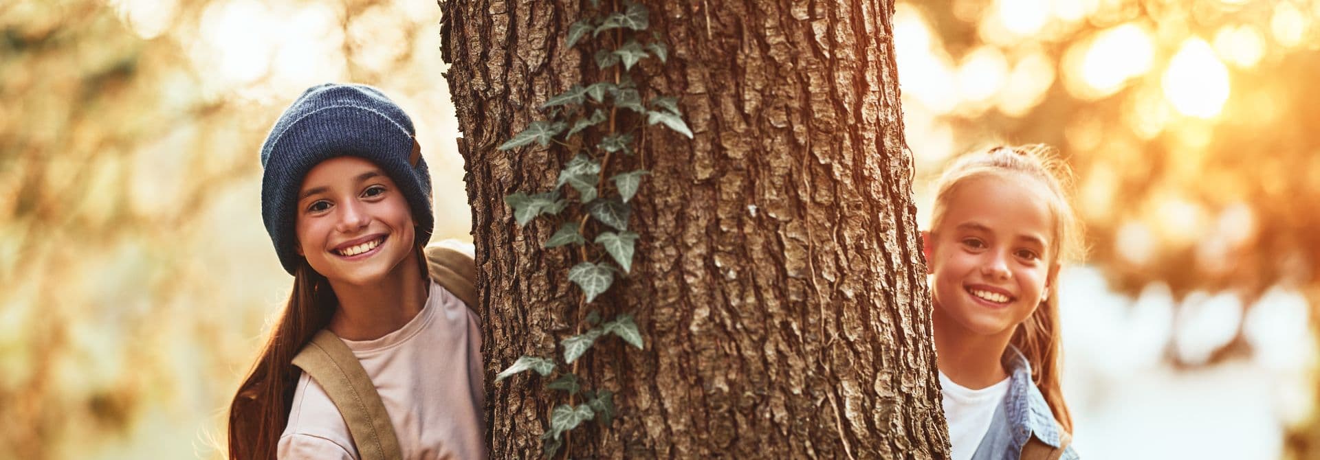 Zwei Mädchen umfassen Baum