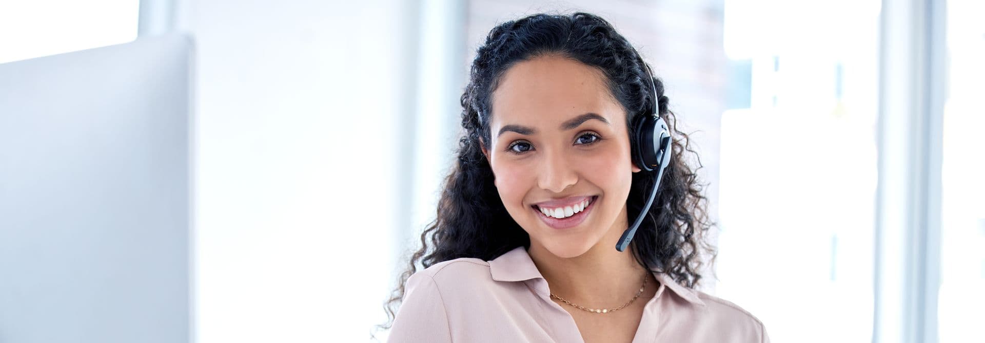 lächelnde Frau mit Headset,  ein Büro im Hintergrund