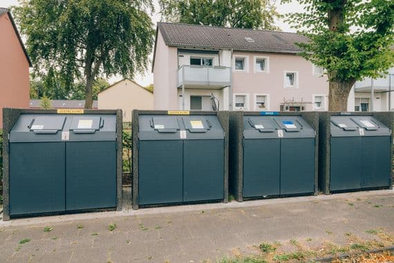 Behälter mehrerer Abfallfraktionen stehen nebeneinander vor einem Wohnhaus