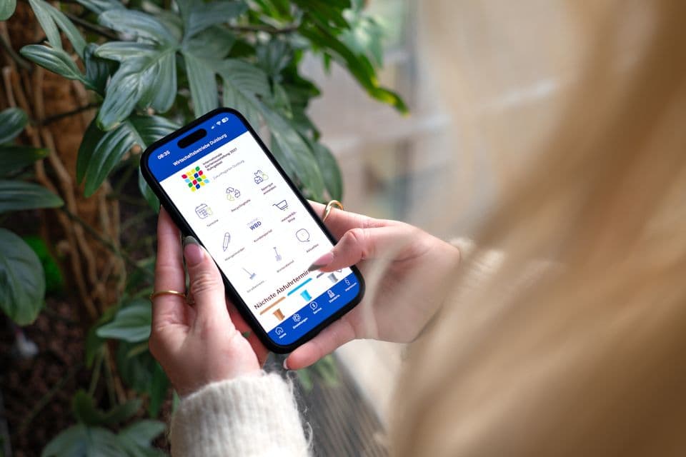Frau hält Smartphone in der Hand, man sieht die geöffnete WBD App.