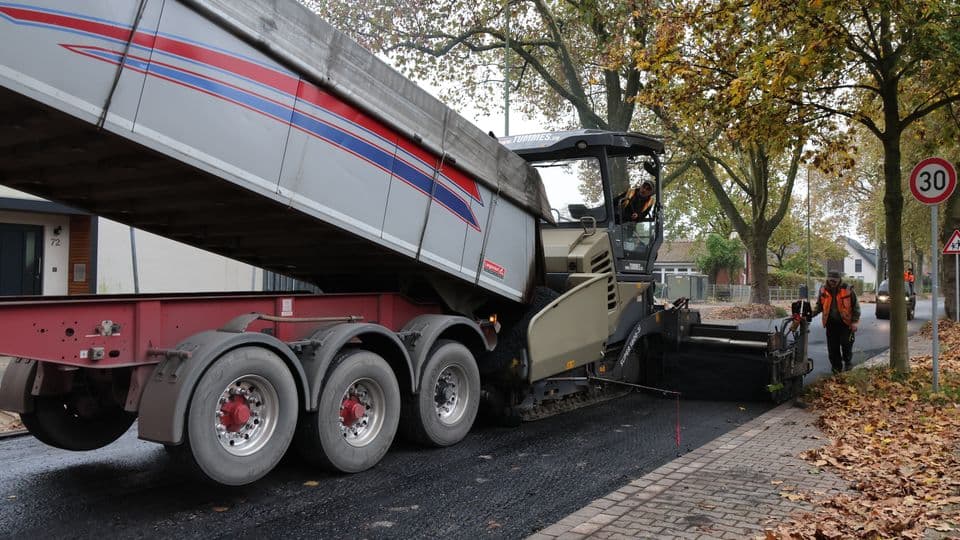 LKW schüttet Material in Straßenbaumaschine