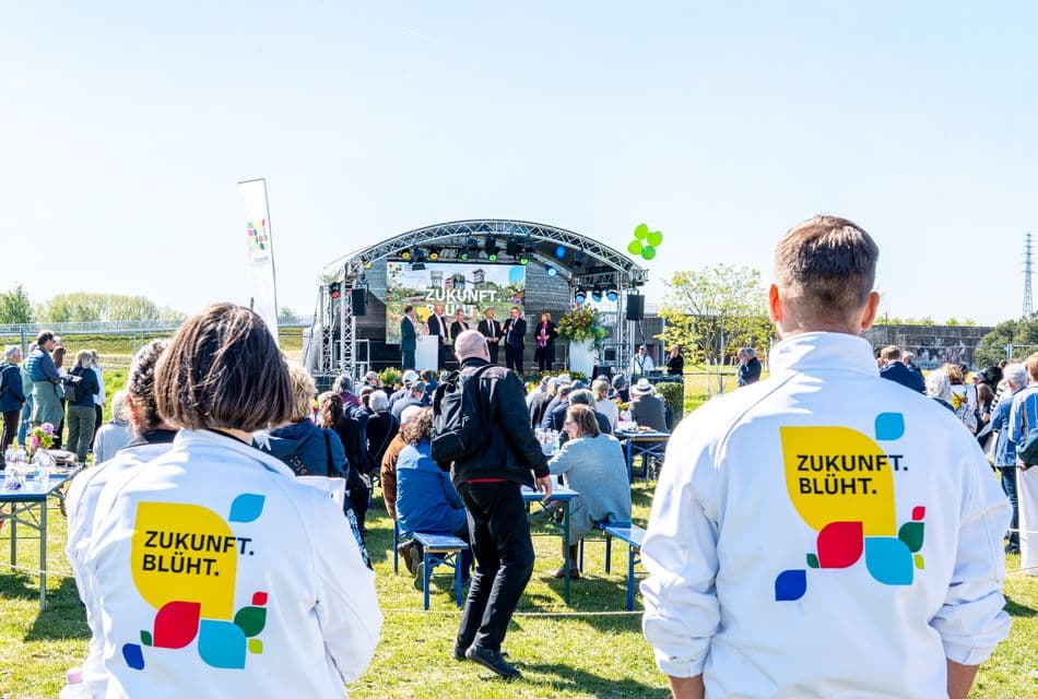 Veranstaltung im Freien, Zukunft blüht , zwei Mitarbeiter schauen zur Bühne