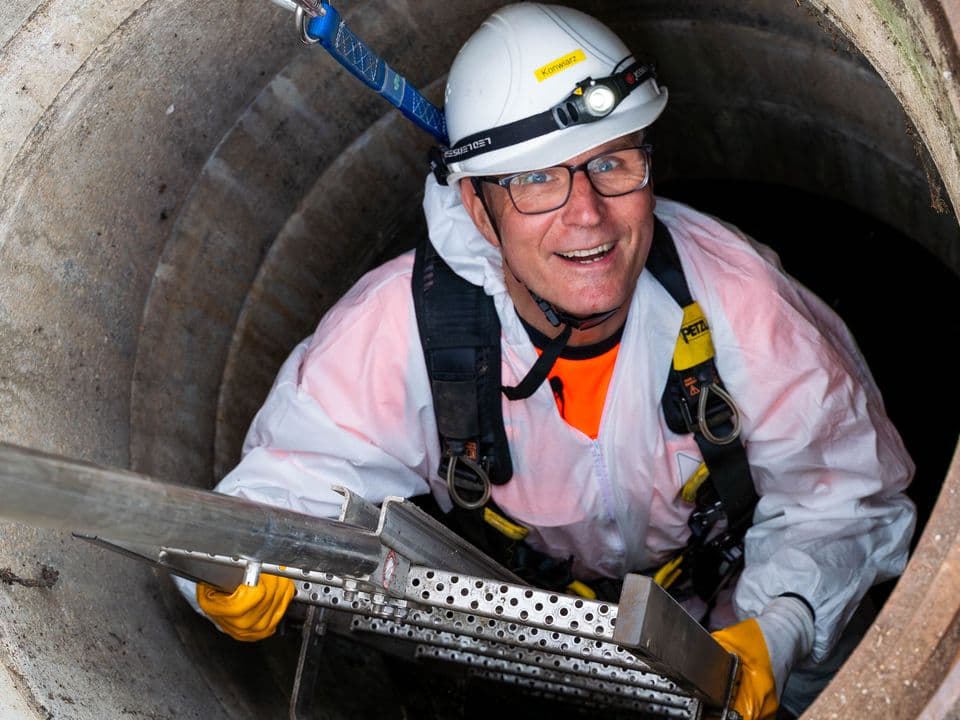 Ein Mitarbeiter der Wirtschaftsbetriebe steigt einen Schacht hinunter