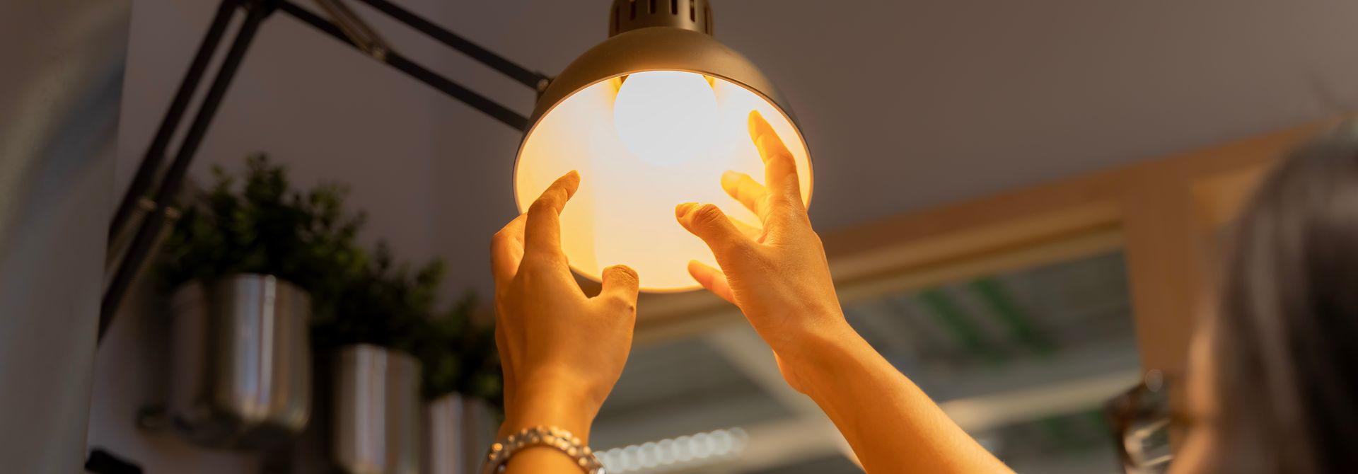 Altlampen Frau schraubt eine Birne in eine Lampenfassung