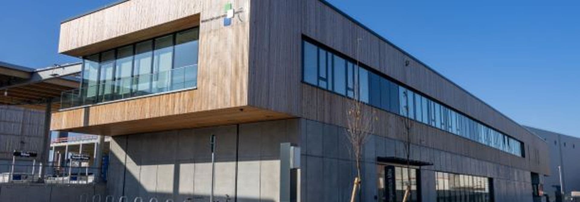 Recyclingzentrum Mitte Das Recyclingzentrum Mitte, ein großes Gebäude mit Holzvertäfelung oben und Fensterreihen.