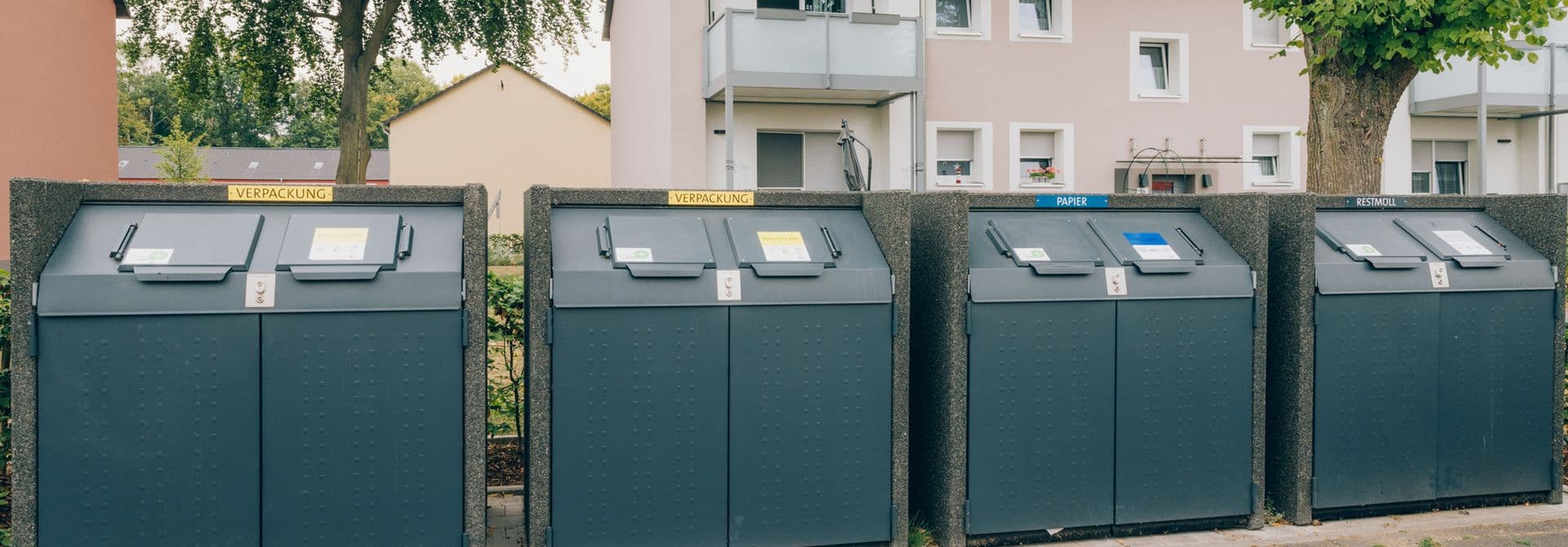 Behälterstandplatz Behälter mehrerer Abfallfraktionen stehen nebeneinander vor einem Wohnhaus