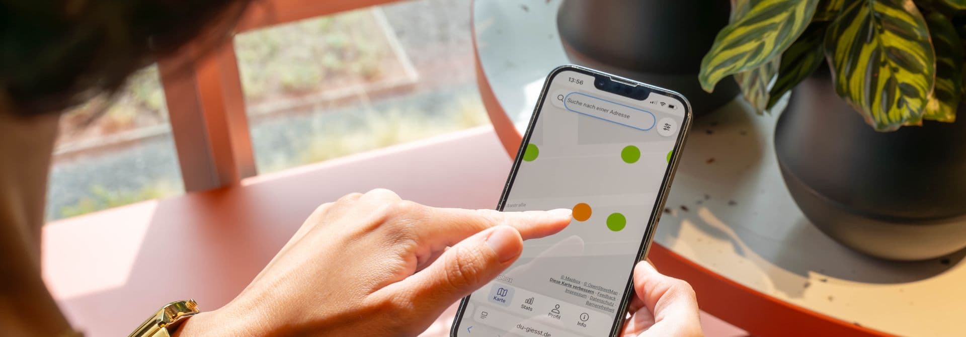 DU gießt Frau tippt mit Finger auf eine Karte auf ihrem Smartphone