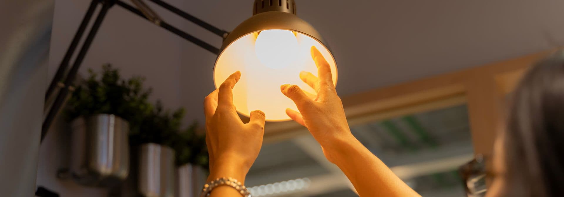Altlampen Frau schraubt eine Birne in eine Lampenfassung