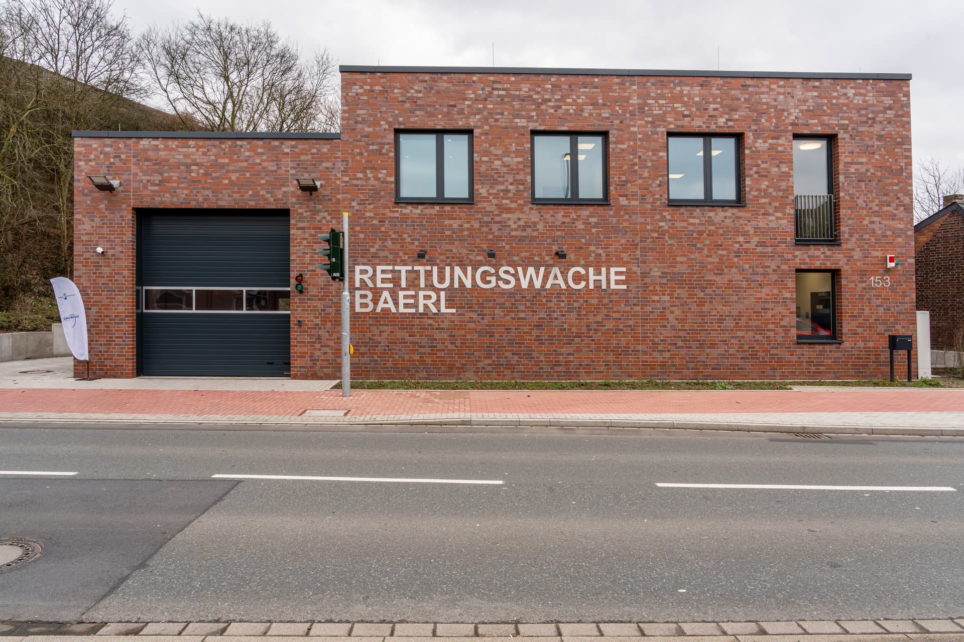 Frontansicht eines rotes Backsteinhauses mit Festern und Fahrzeugeinfahrt